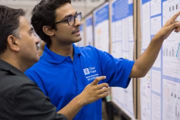 Two people looking at instructional material on the wall 